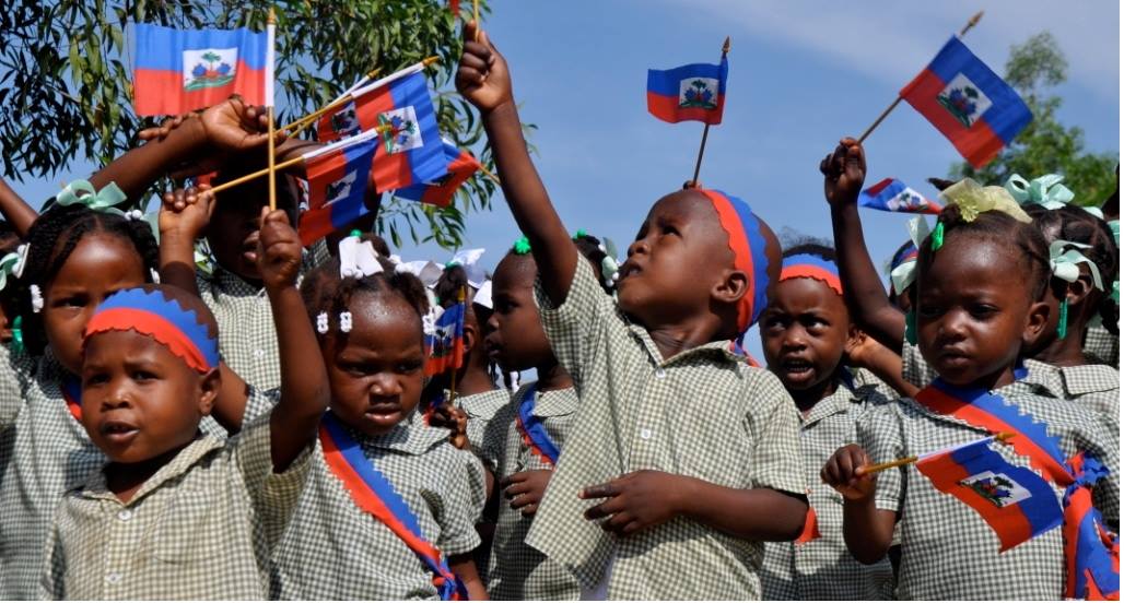 Haïtiaanse kinderen zwaaien met vlaggetjes
