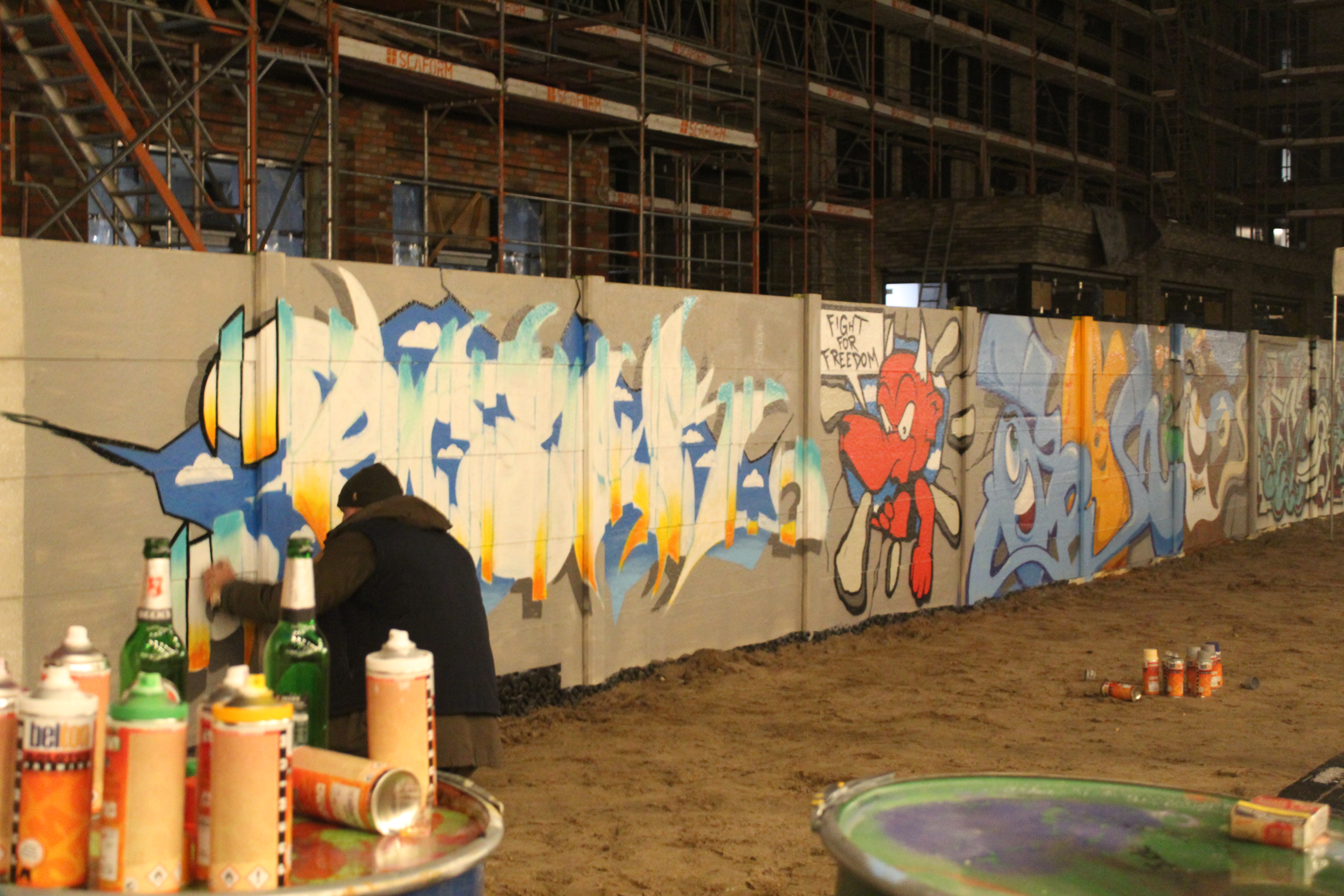 Grafitti artiesten bewerken een muur in Berlijn